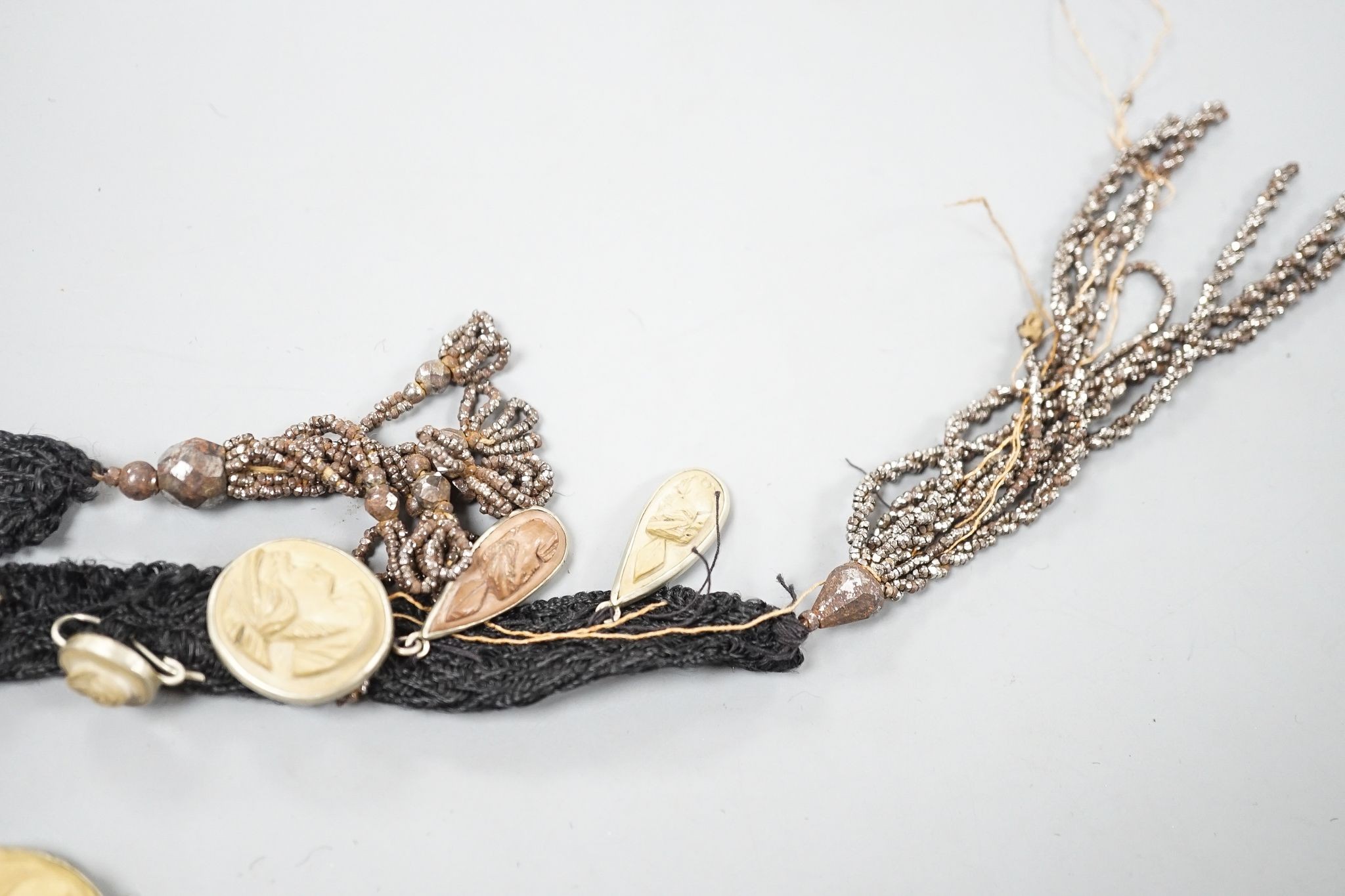 A group of graduated base metal mounted mainly oval lava cameos(thirty eight in total), mounted as on a sash necklace, with cut steel tassel terminals, length 115cm.